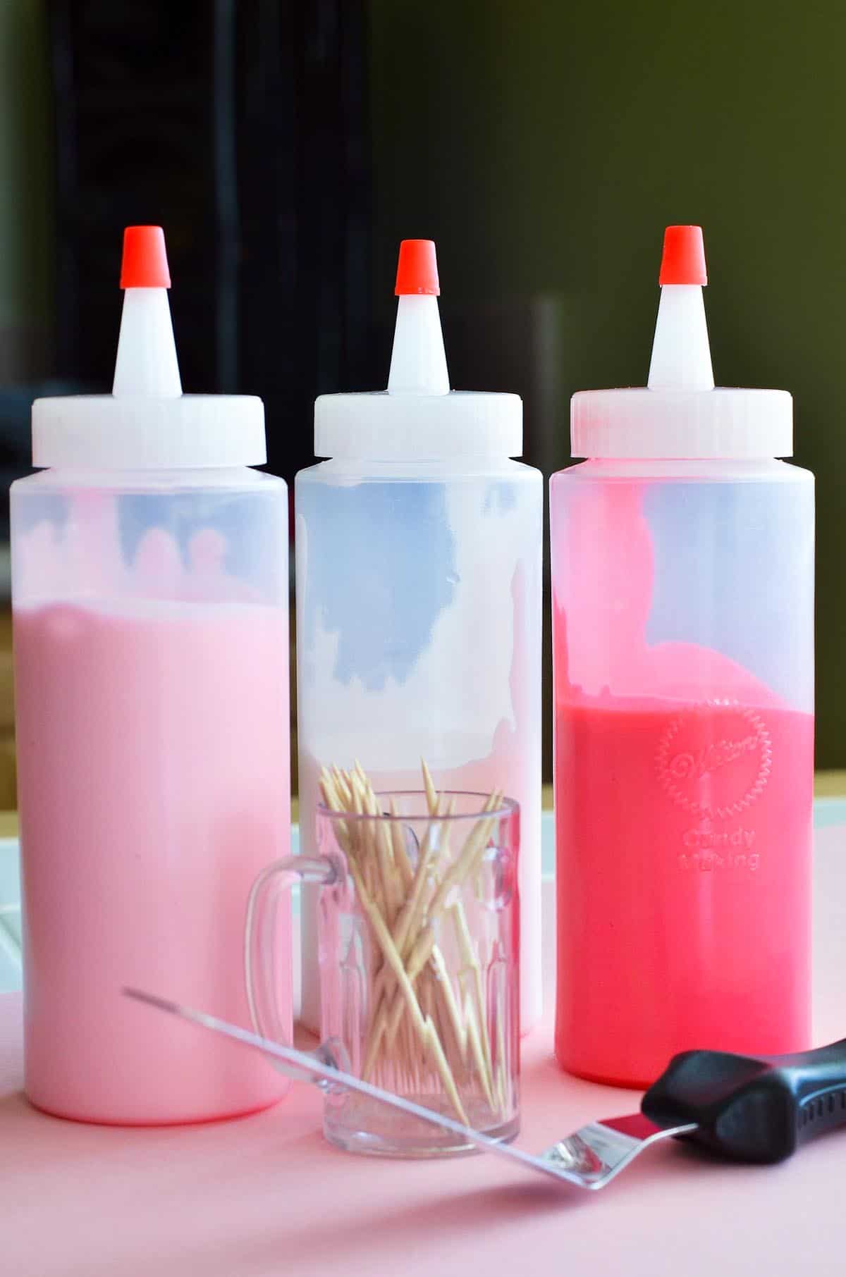 three squeeze bottles with icing and toothpicks with offset spatula