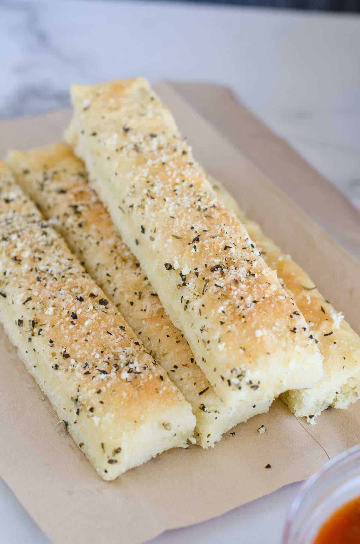homemade breadsticks stacked on parchment paper
