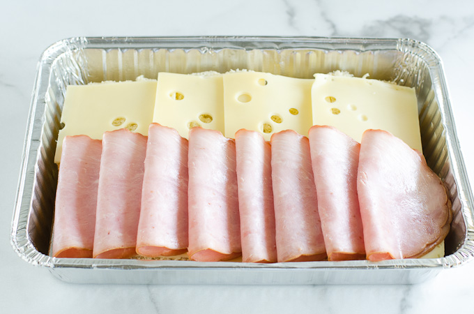 ham and cheese slices layered in foil baking pan