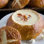 beer cheese soup in a pretzel bowl garnished with bacon