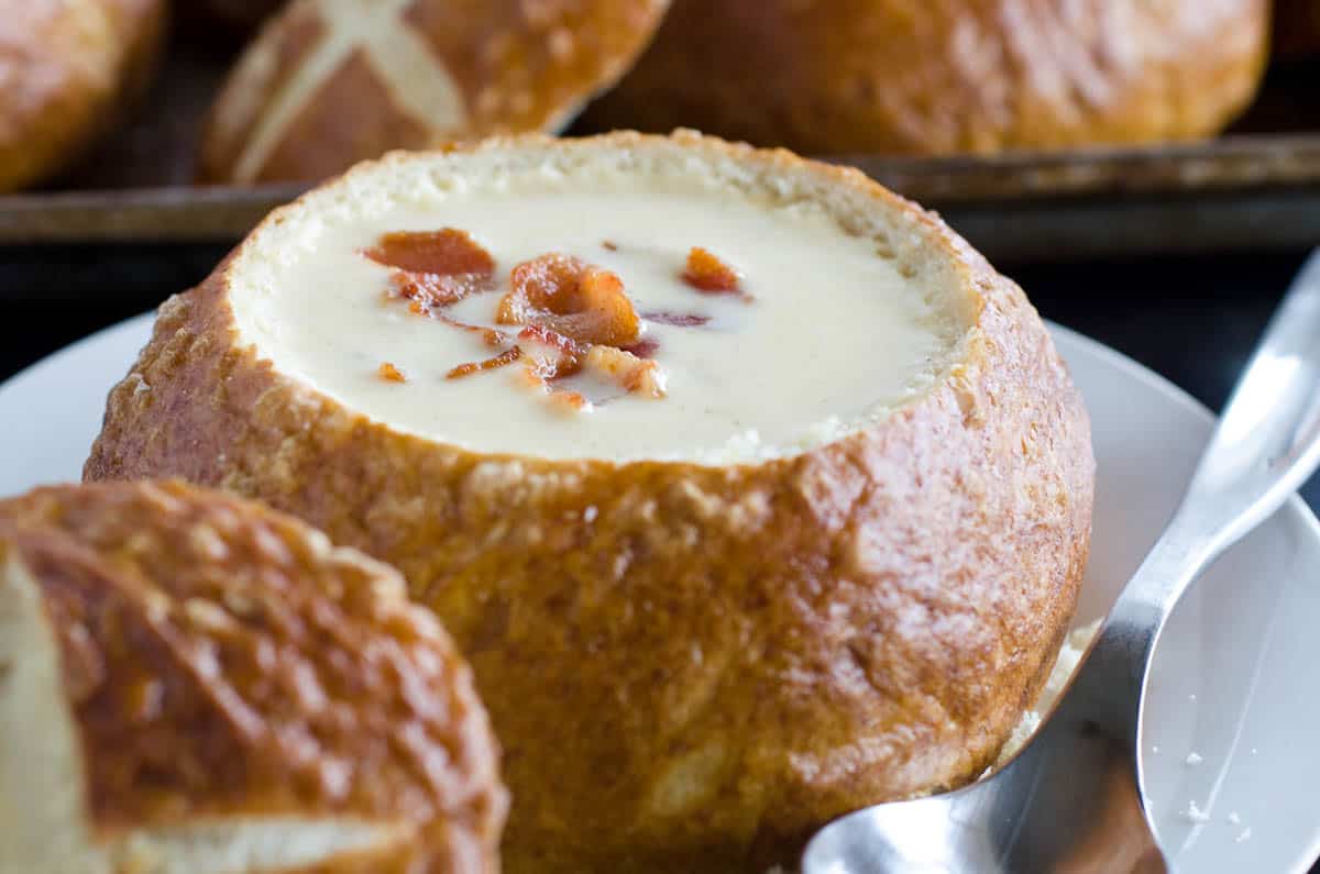 beer cheese soup in pretzel bread bowl with spoon on side