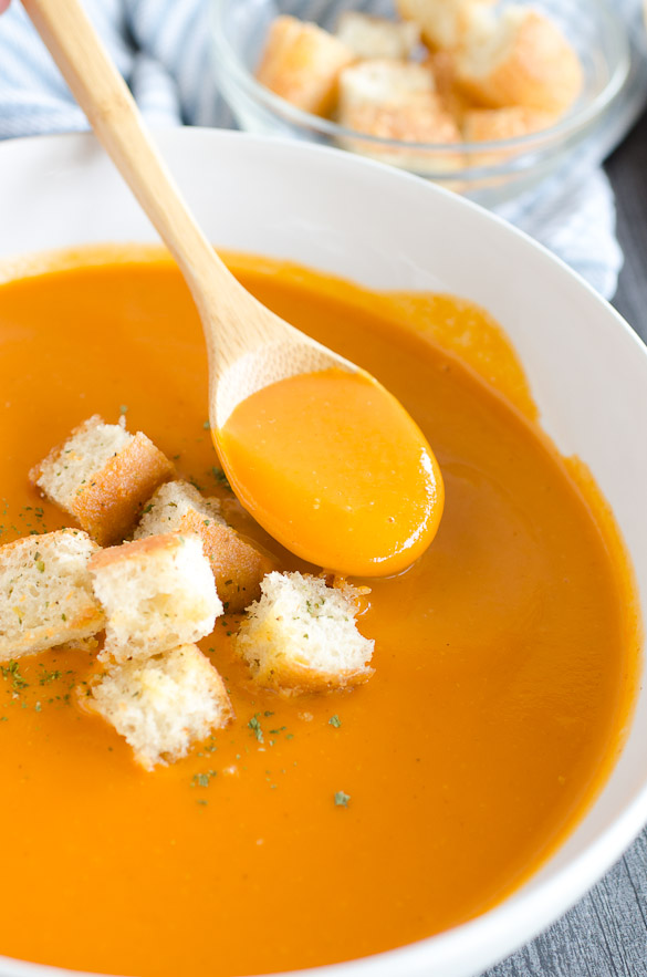 spoon in a bowl of tomato soup with croutons