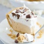 slice of peanut butter pie topped with cool whip and chopped reeses cups