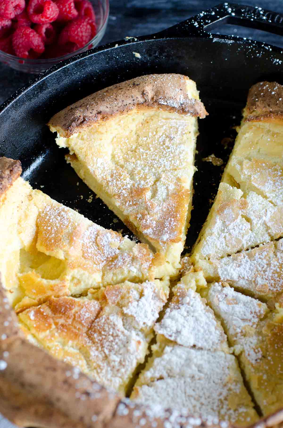 german pancake in cast iron skillet cut into wedges