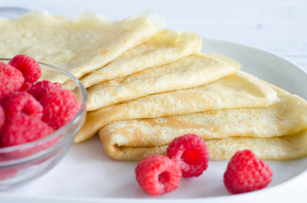 crepes folded on plate with raspberries