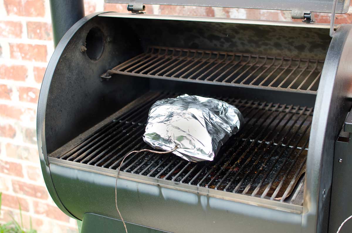 meat on grill wrapped in foil with thermometer
