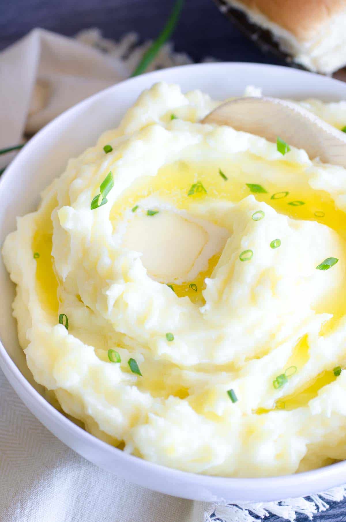 buttery mashed potatoes in a bowl with wooden spoon