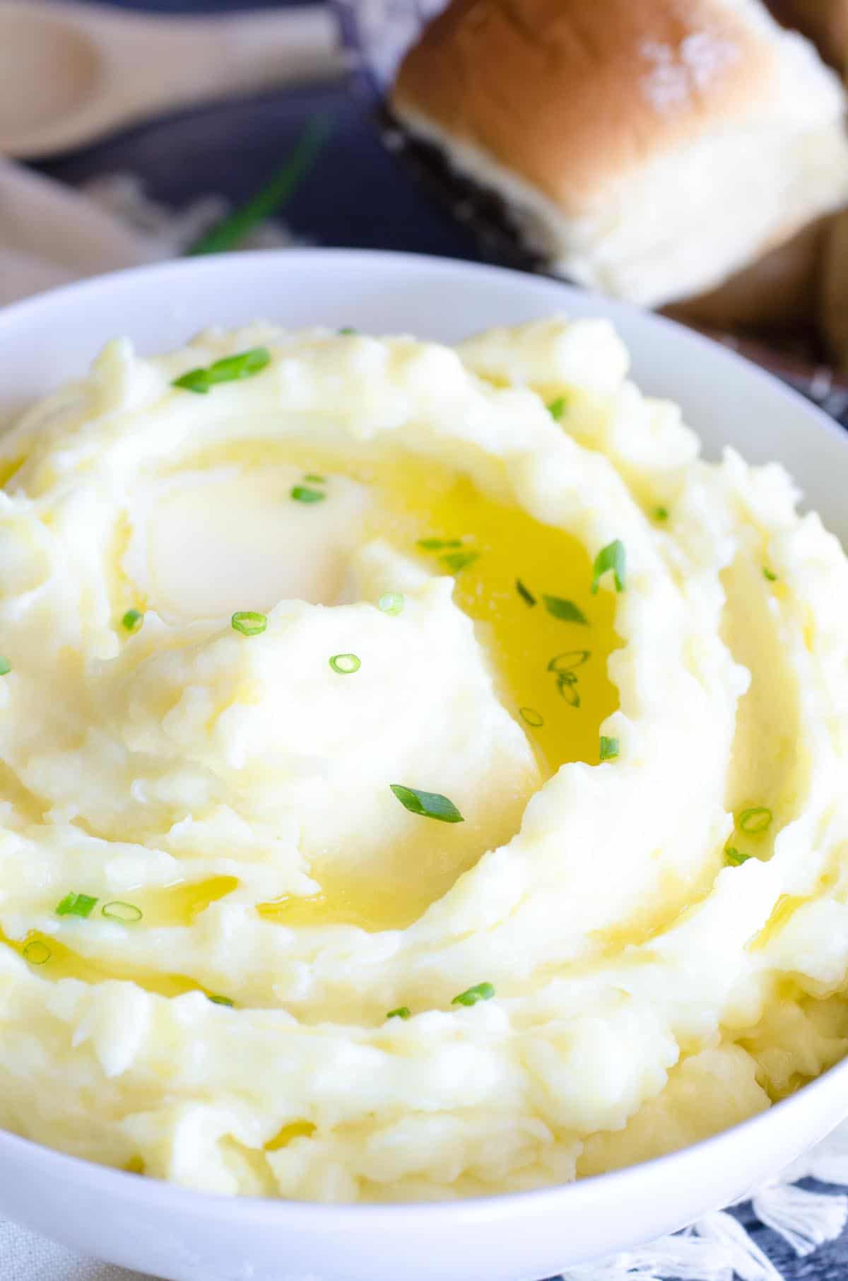 bowl of mashed potatoes with melted butter and chives on top