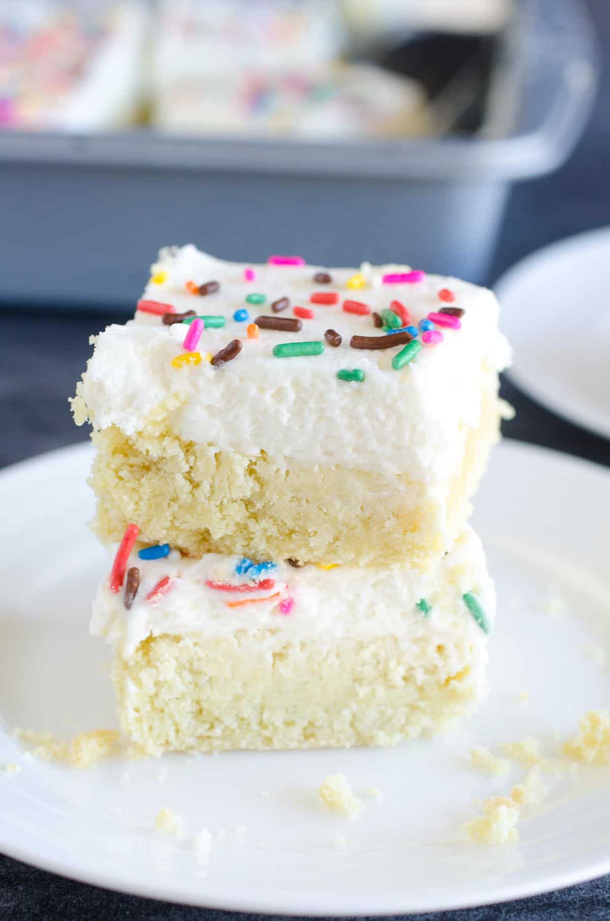 stack of two frosted sugar cookie bars with sprinkles on a plate