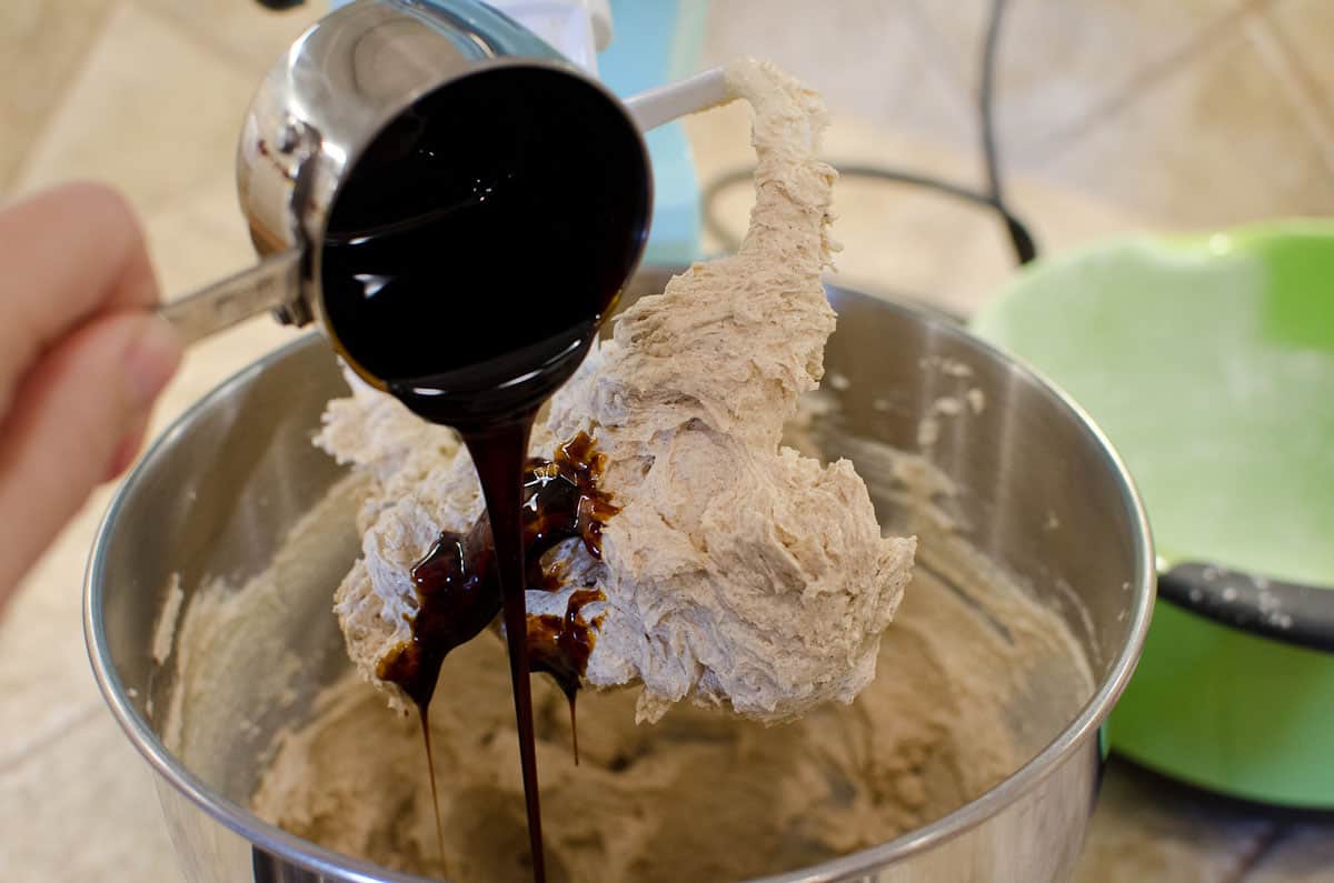 pouring molasses into gingerbread cookie dough