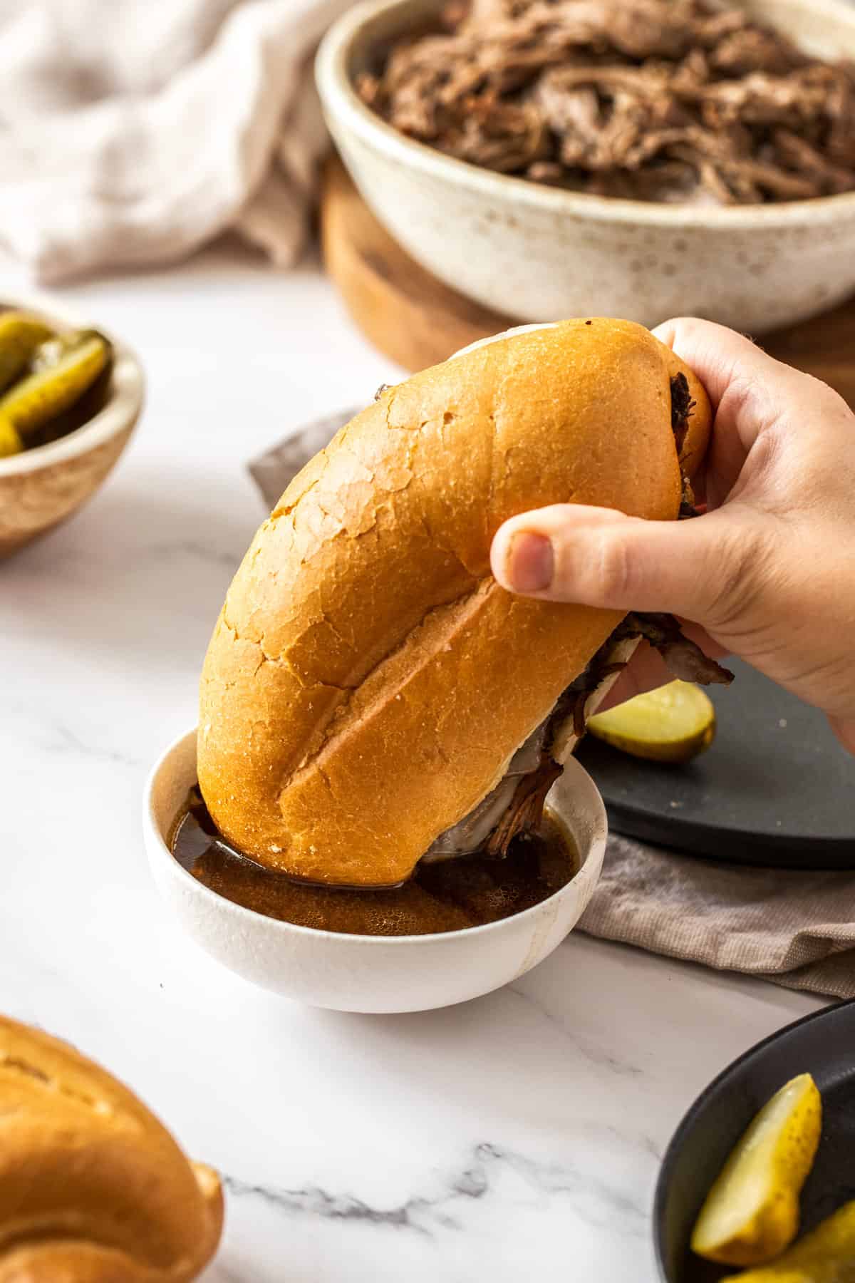 french dip sandwich dipped into bowl of au jus