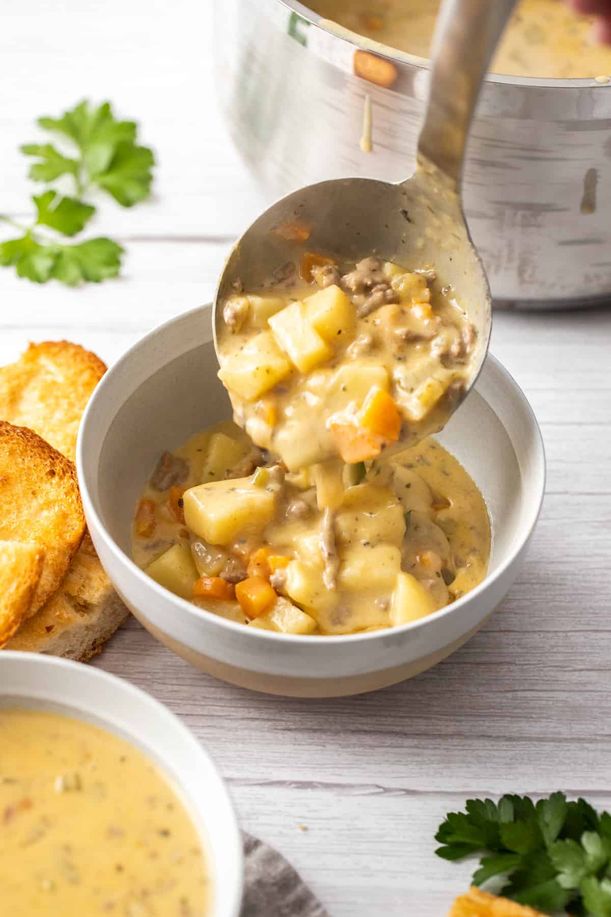 ladle scooping cheeseburger soup into bowl