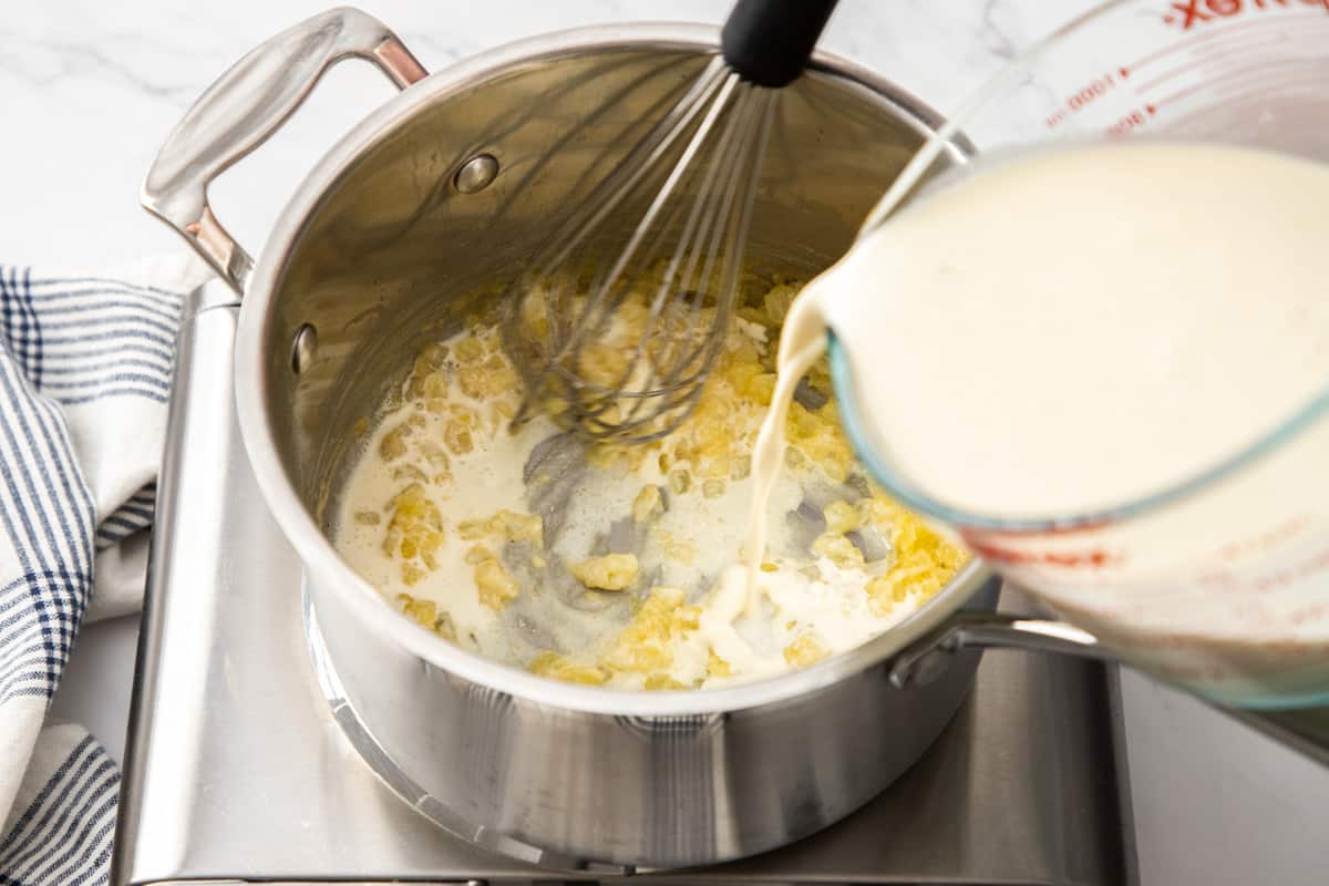 pouring cream into hot pan with cooked onions