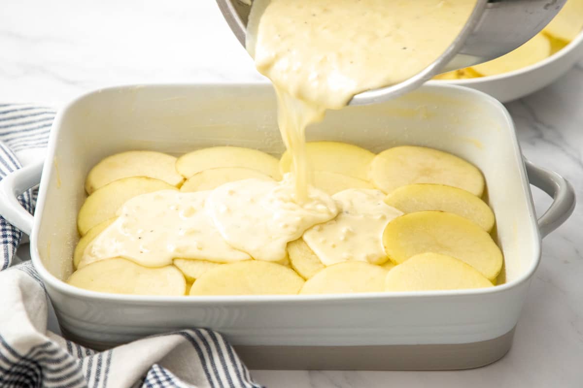 layering potatoes with cream into casserole dish
