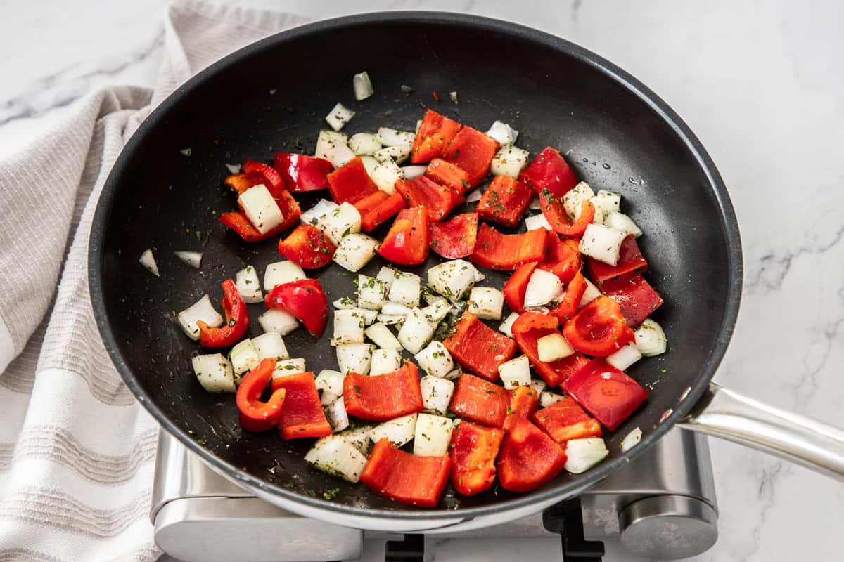chopped peppers and onions in large skillet with herbs for ratatouille recipe