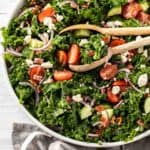 kale salad with tongs in a bowl