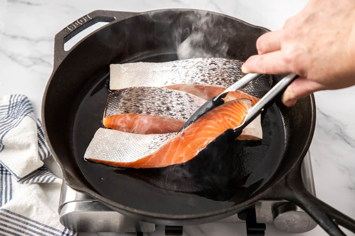 salmon fillets in hot skillet with skin on
