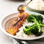 spooning glaze on salmon with white rice and broccolini