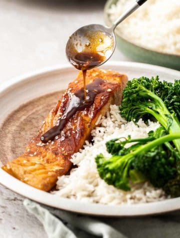 spooning glaze on salmon with white rice and broccolini