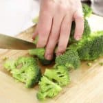 cutting broccoli florets on wooden board
