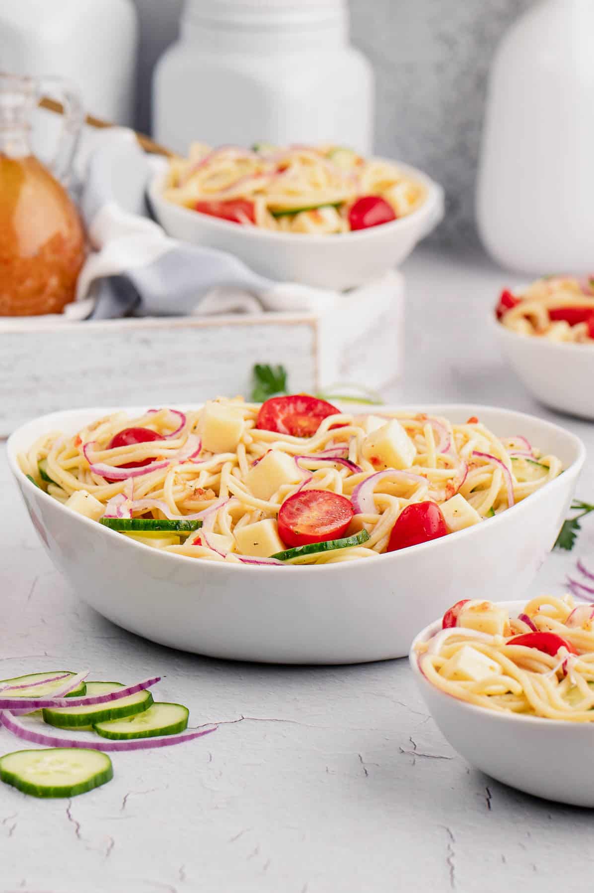bowls of spaghetti noodles with tomatoes and cucumbers
