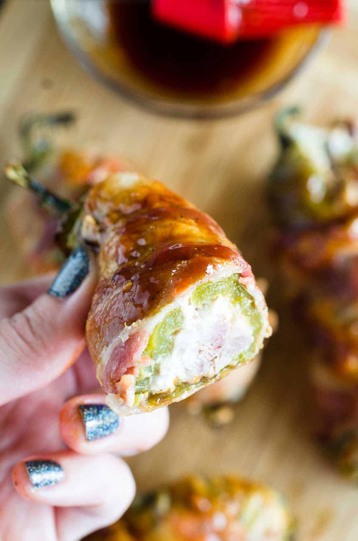 holding a cream cheese and brisket stuffed jalapeno wrapped in bacon