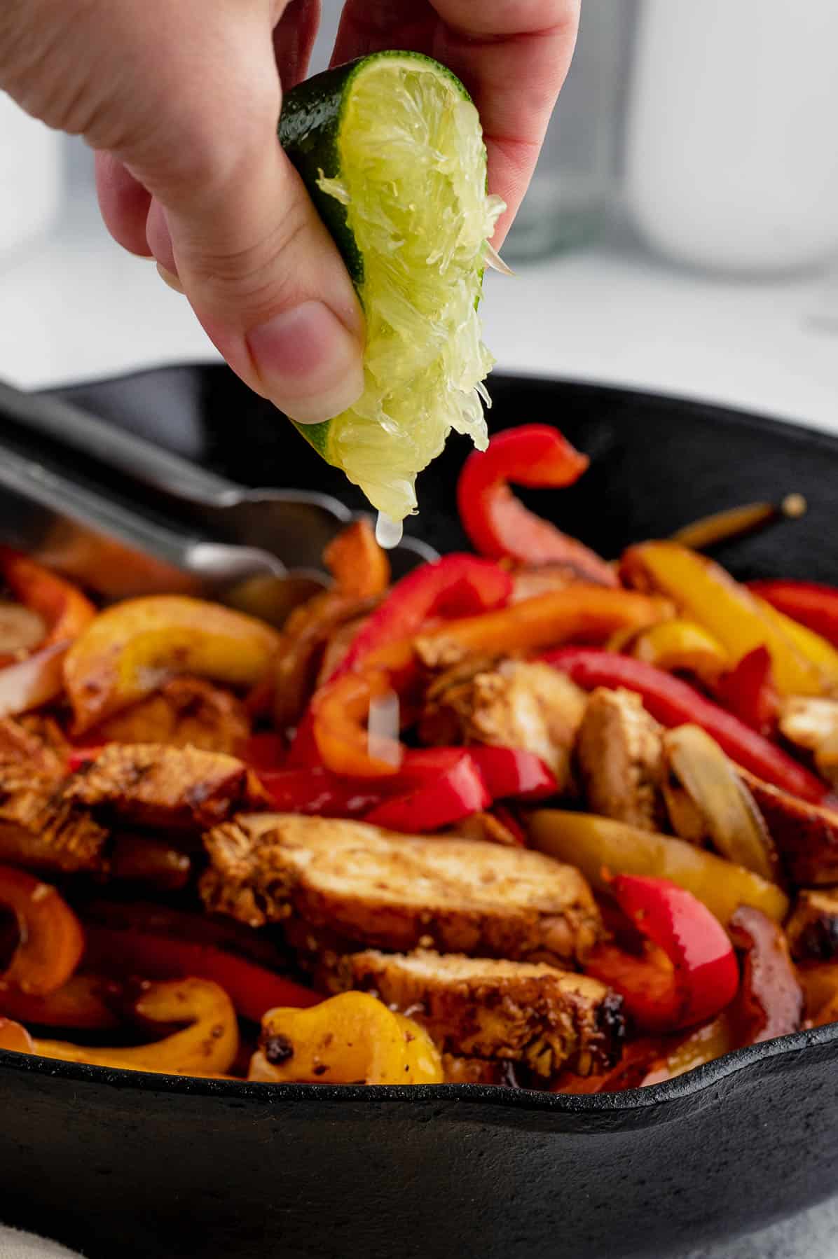 squeezing fresh lime juice over cooked chicken slices and peppers