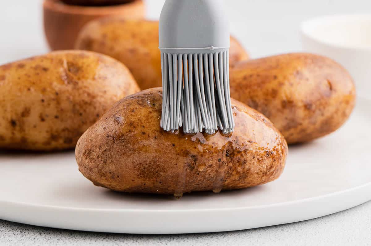 brushing oil on russet potatoes with pastry brush