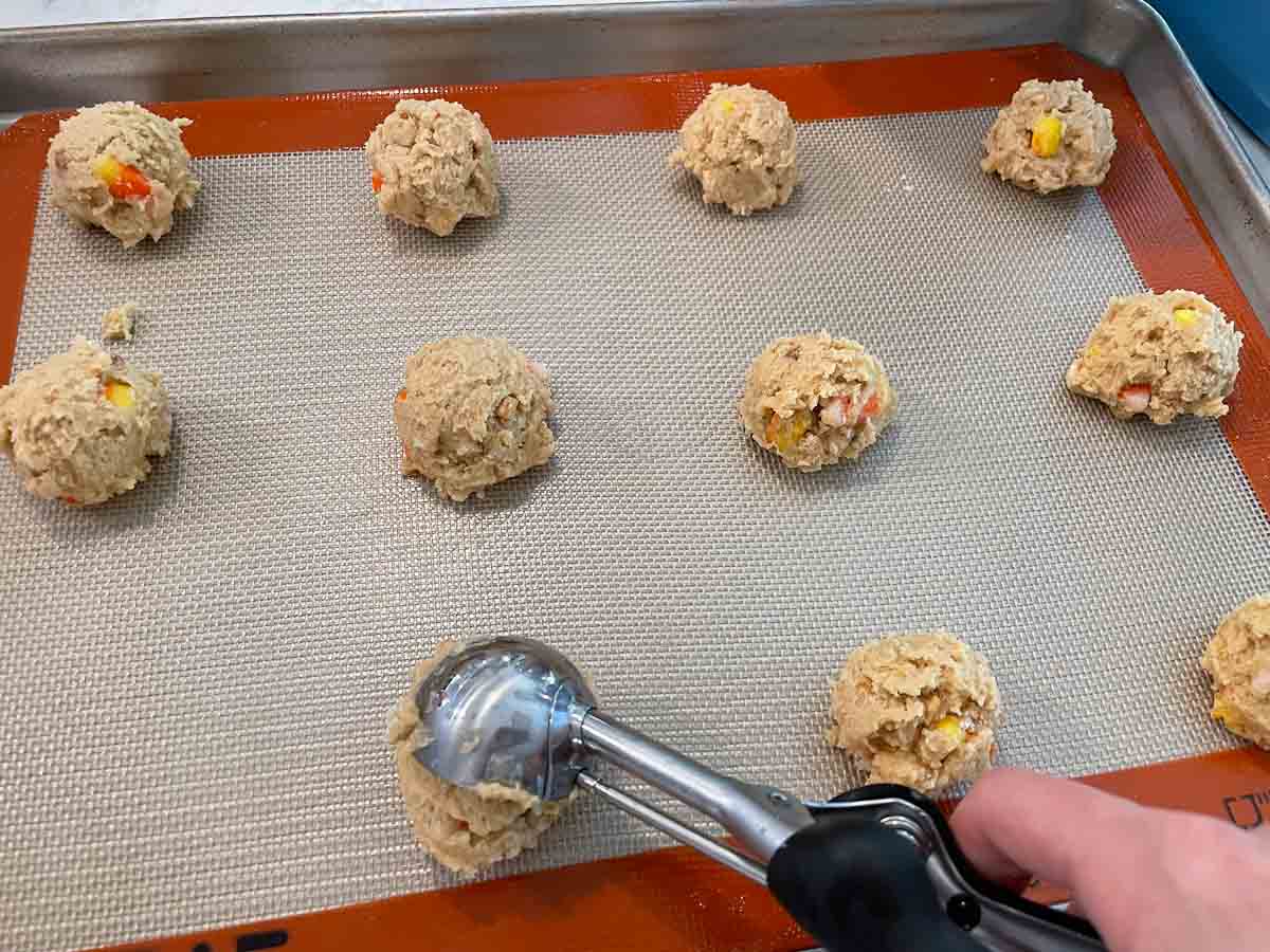 dropping cookie dough balls onto baking sheet with cookie scoop