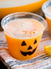 orange punch in a plastic cup with a jack o lantern face