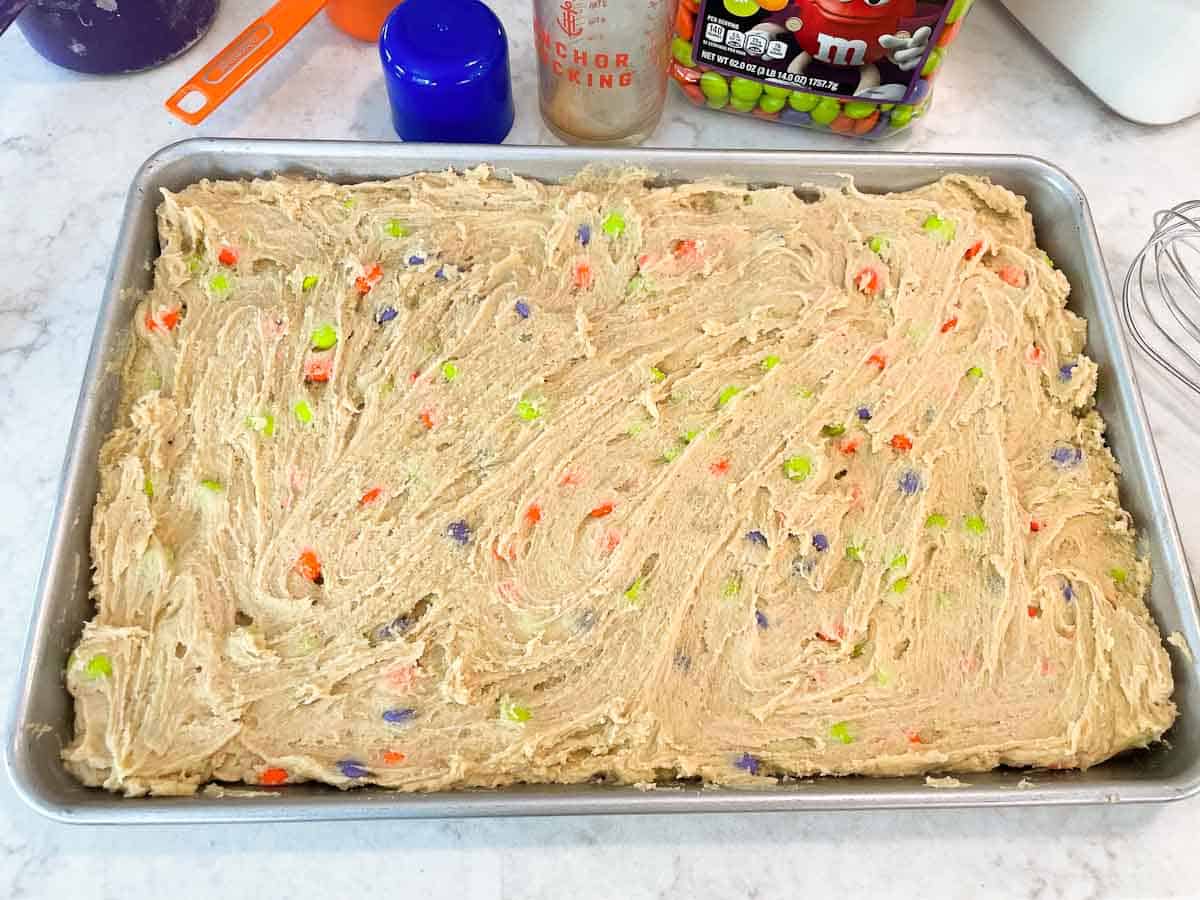 raw cookie dough spread in large rimmed baking sheet