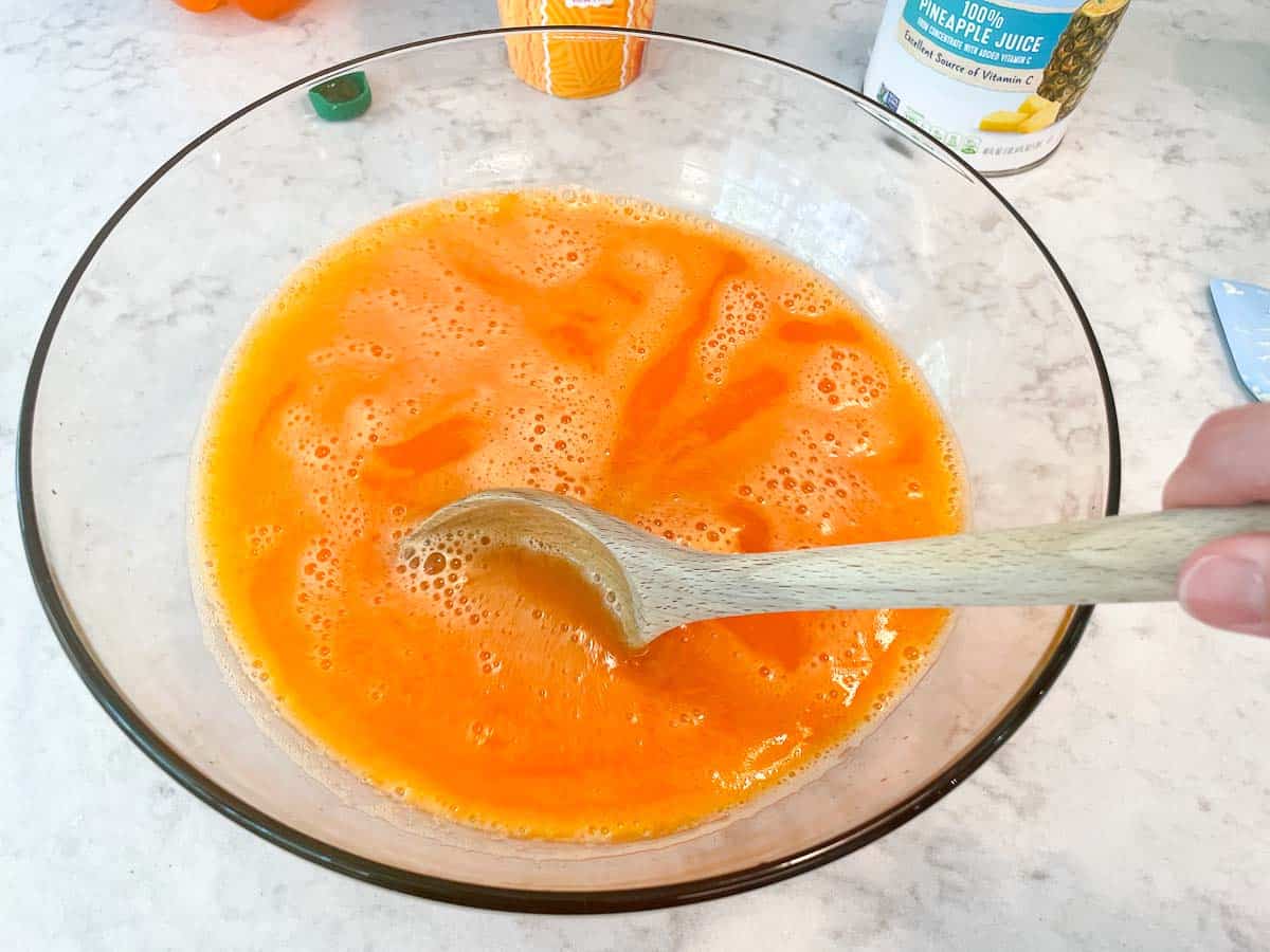 mixing orange punch in large punch bowl with wooden spoon