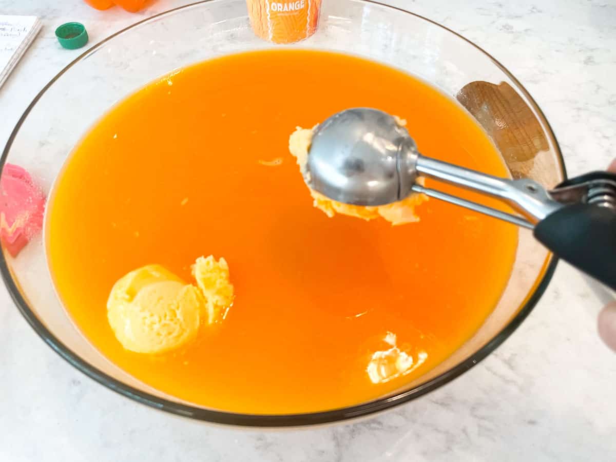 scooping orange sherbet into orange punch