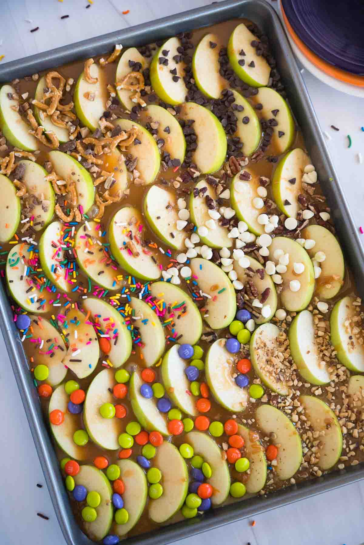 sheet pan with sliced caramel apples and toppings