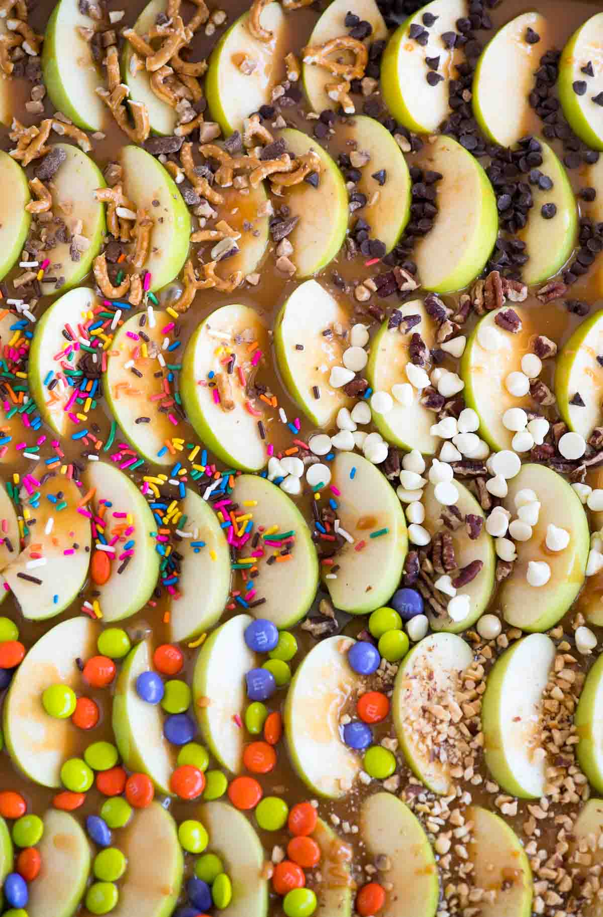 caramel apple slices on a sheet pan with candy toppings