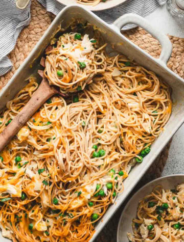 chicken spaghetti baked in a casserole dish with wooden spoon to serve