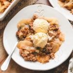 bowl of apple crisp with scoops of vanilla ice cream on top