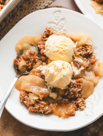 bowl of apple crisp with scoops of vanilla ice cream on top