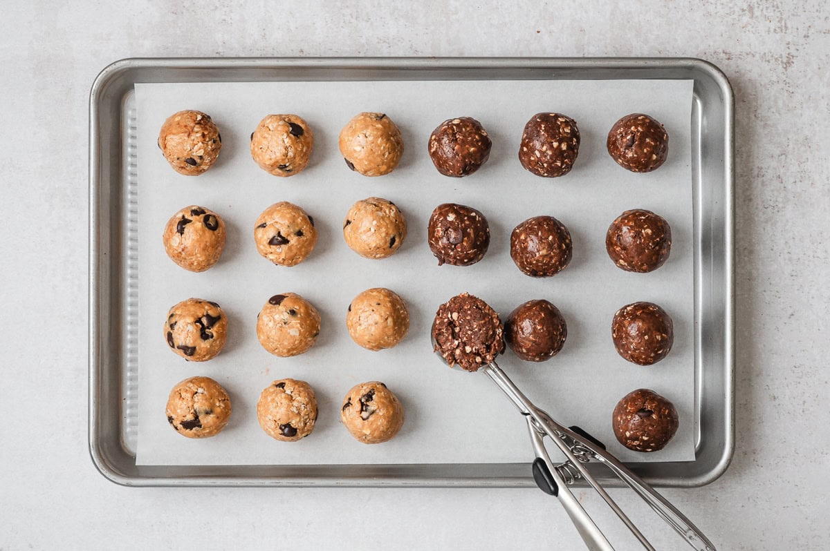 scoops of chocolate chip and peanut butter protein balls on a baking sheet