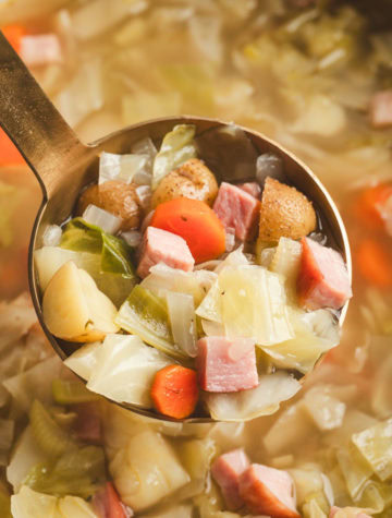 ladle of cabbage and ham soup from pot