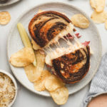 corned beef reuben sandwich on a round plate with potato chips