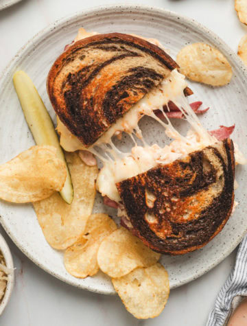 corned beef reuben sandwich on a round plate with potato chips